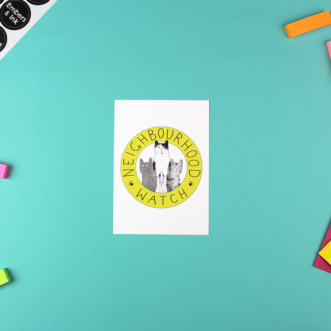The neighbourhood watch cats postcard is shown on a table.