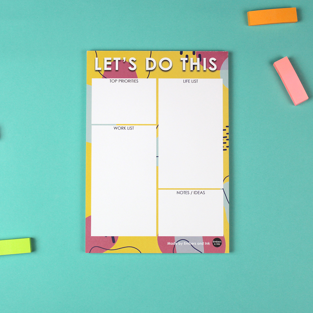 The Let's Do This A5 Notepad is pictured on a colourful desk.