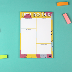 The Let's Do This A5 Notepad is pictured on a colourful desk.