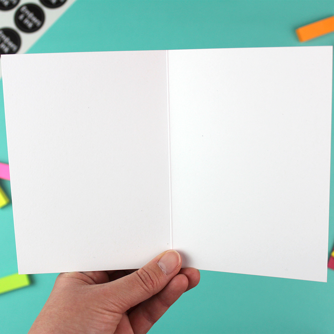 A hand holds open the greeting card to show that it is blank inside and has loads of room for your own message. nice.