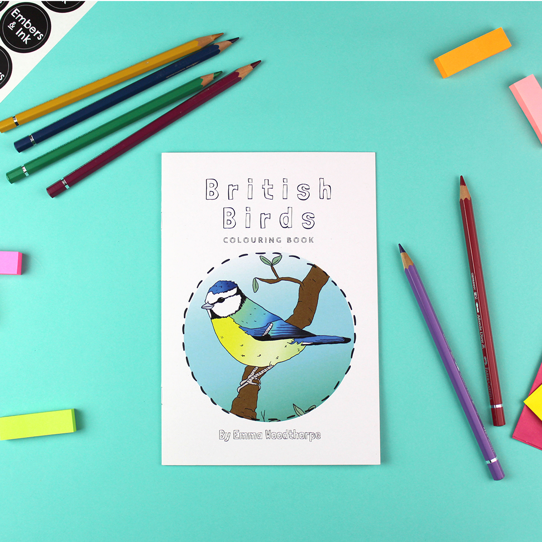 The british birds colouring book lays on a table among coloured pencils