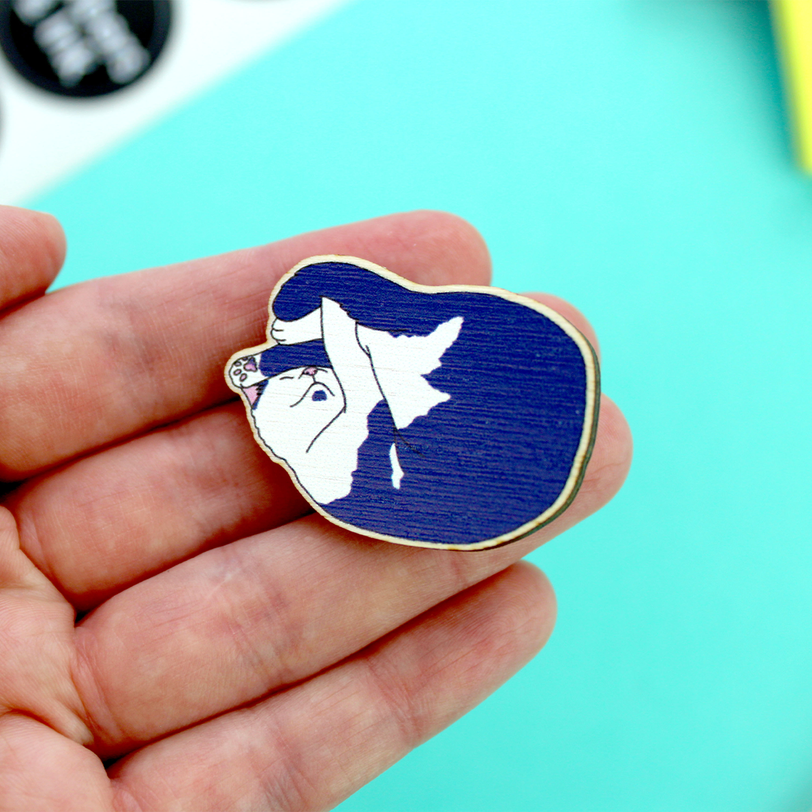 The wooden cat pin badge is photographed in an open hand as an indicator of size (41mm x 30mm approximately)
