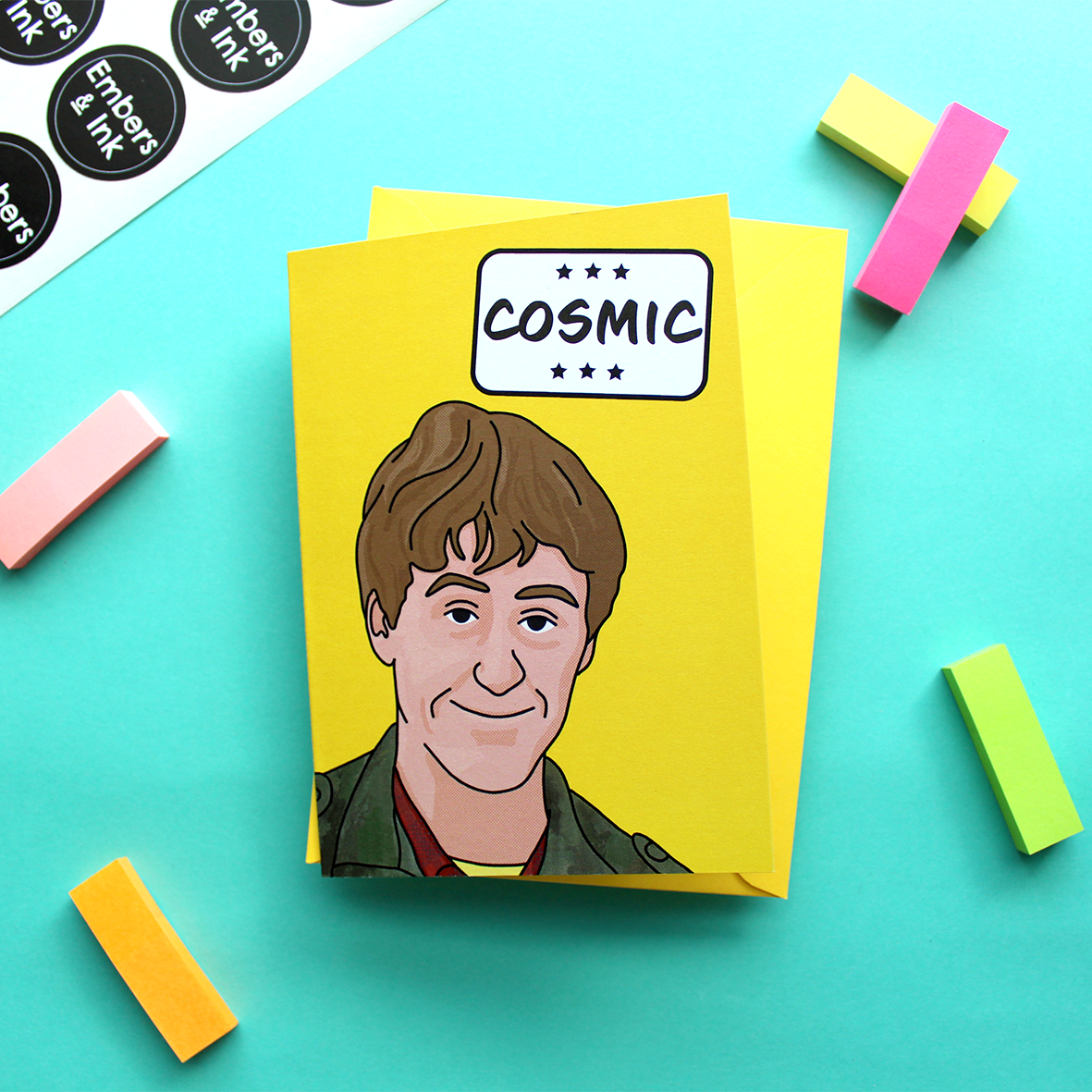 a yellow card with an illustration of Rodney from a well known TV program underneath the word 'Cosmic' in a white box