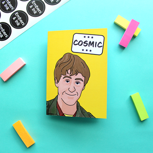  a yellow card with an illustration of Rodney from a well known TV program underneath the word 'Cosmic' in a white box