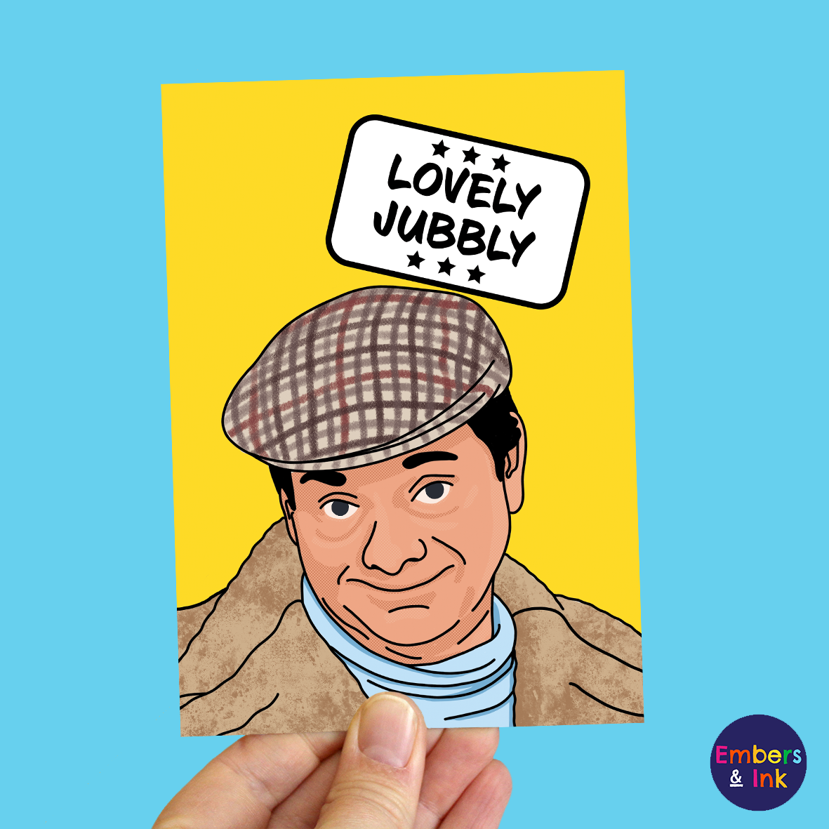 A hand holds a yellow card with an illustration of Del Boy from a well known 80s TV programme. Above him in a white box are the words ‘Lovely Jubbly’
