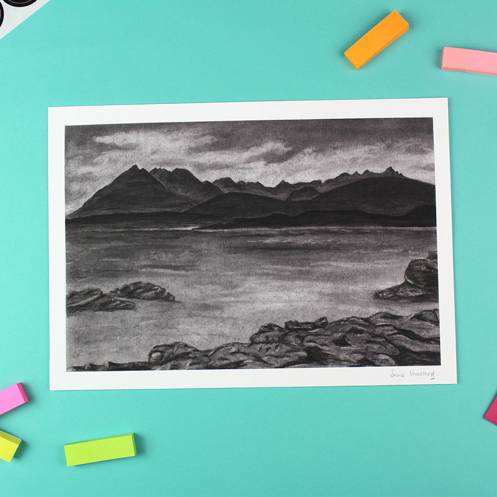 The picture shows a landscape orientated printt of a charcoal drawing of the cuillin mountain range over a stretch of water.