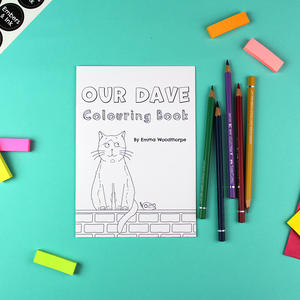 The Our Dave colouring Book is on a table next to a collection of coloured pencils