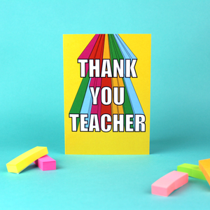 The image shows a bright and colourful Greetings Card standing against a green background. The card has a yellow background and rainbow coloured 3D lettering that reads Thank You Teacher.
