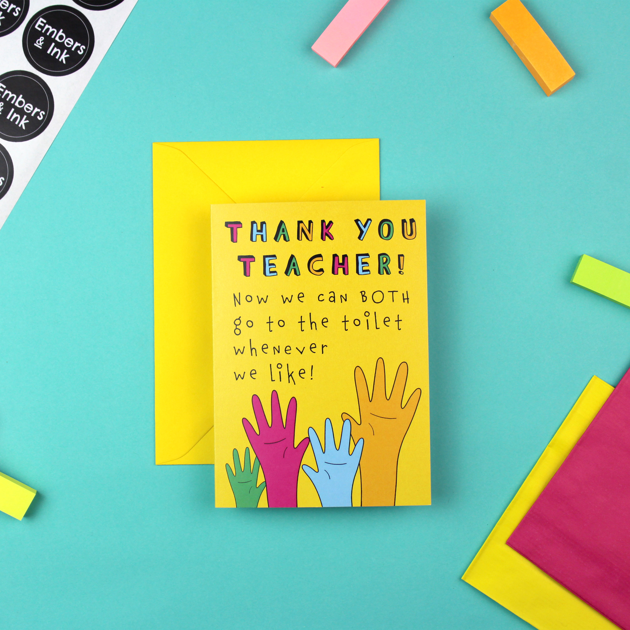 Image shows a yellow card with a yellow envelope. The card has an illustration of four raised hands in green, pink, blue and orange. Above the hands are the words 'Thank You Teacher, now we can both go to the toilet whenever we like'.