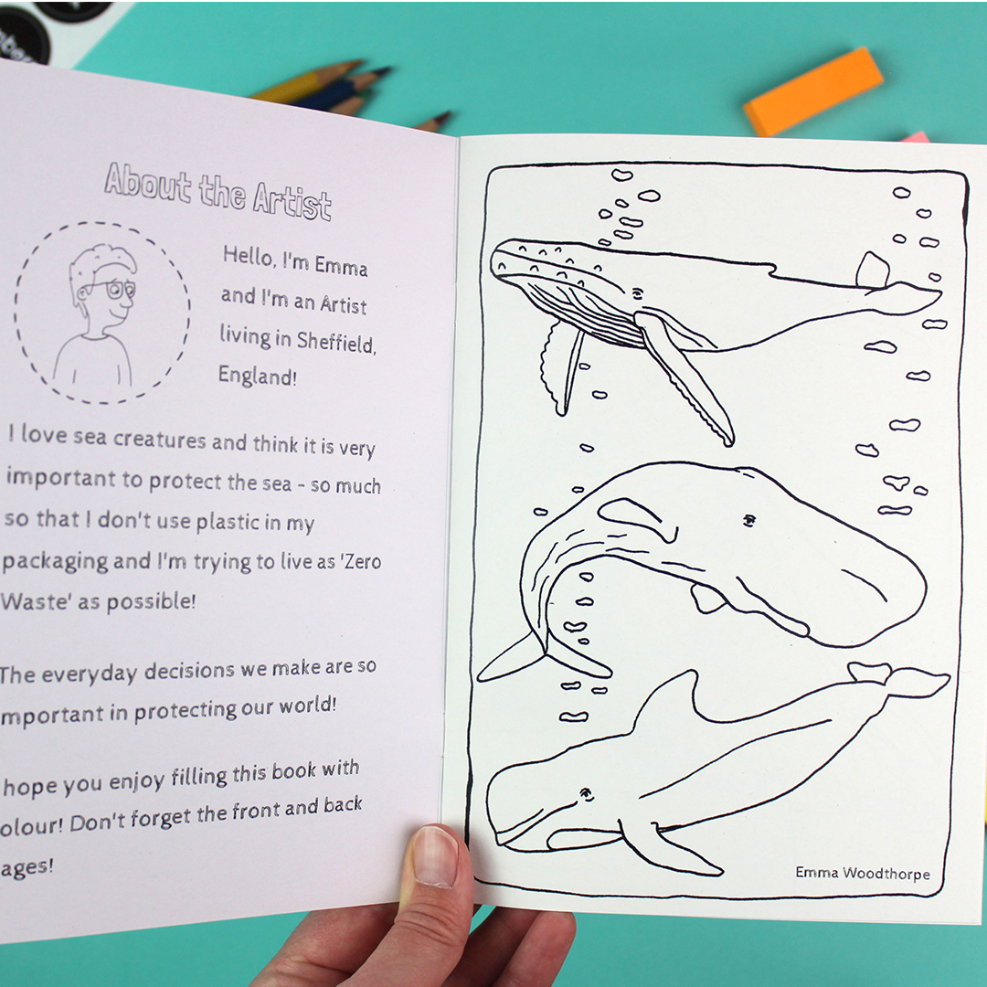 a hand holds open the colouring book that shows a welcome message on the inside cover and the first page image f three whales. both can be coloured in.
