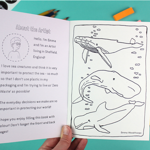 a hand holds open the colouring book that shows a welcome message on the inside cover and the first page image f three whales. both can be coloured in.