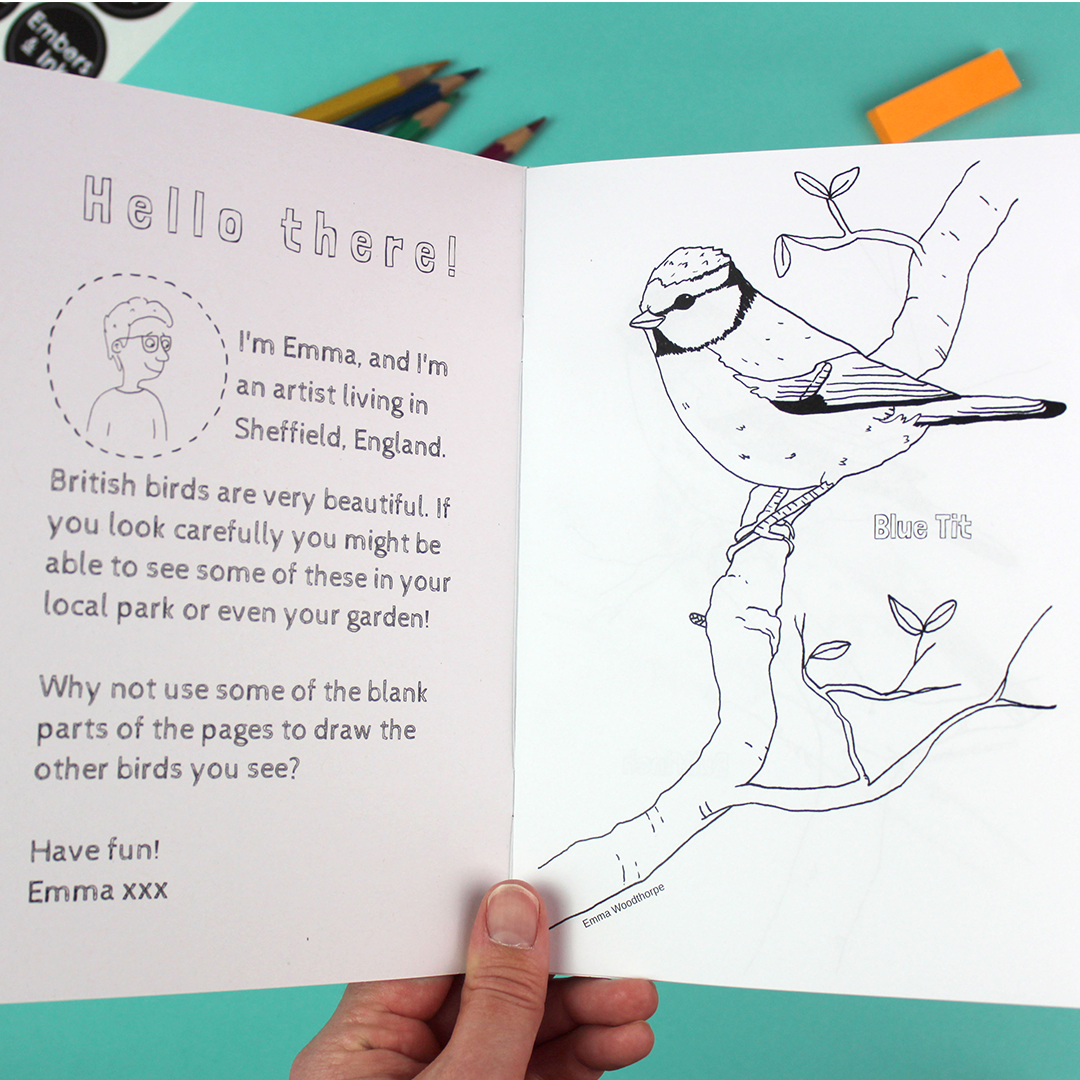 A hand holds open the colouring book to show an introduction on the inside cover and the first page with an image of a blue tit. both are black and white and can be coloured in.