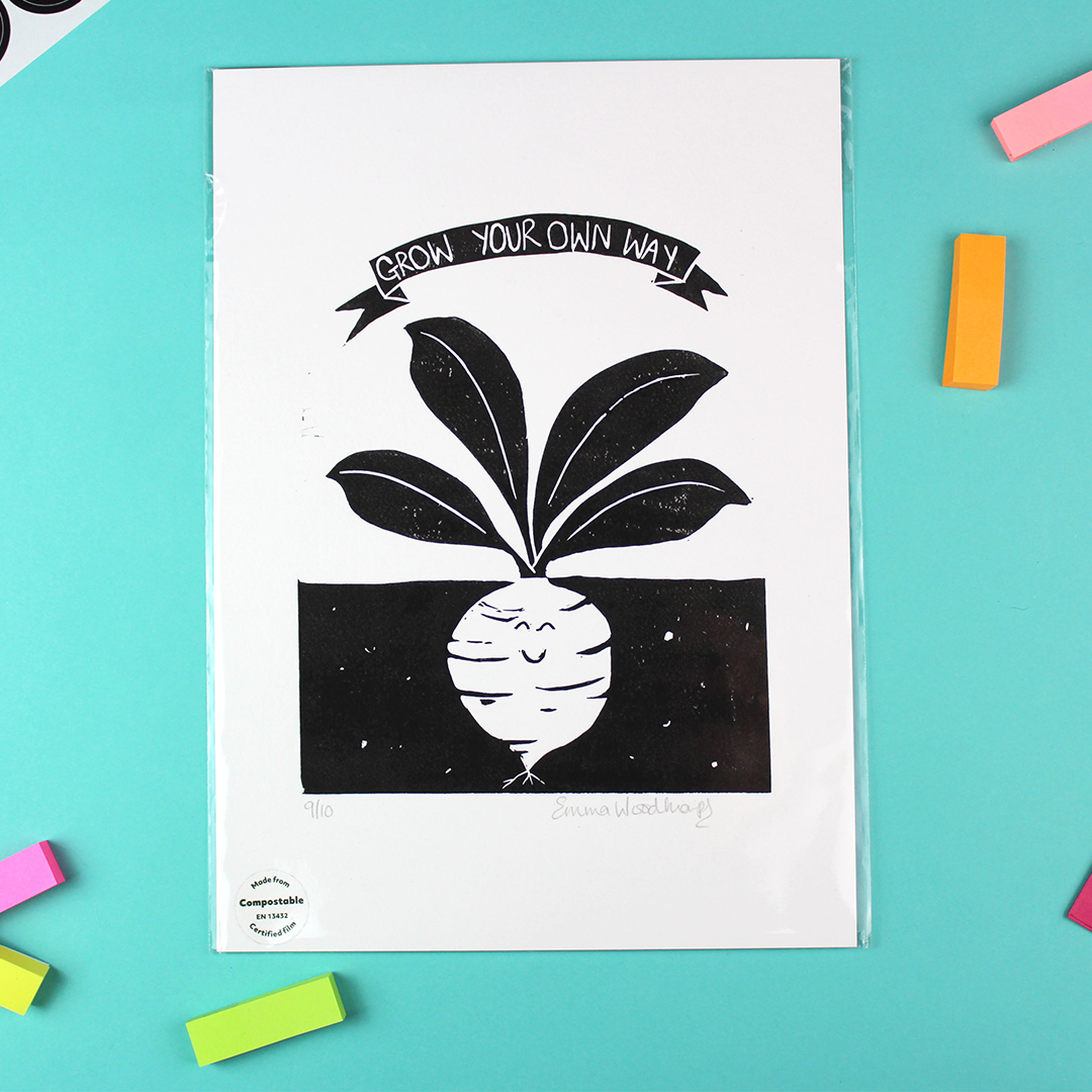 Image shows a portrait-orientated black and white lino print of a root vegetable with a smiley face: the bulb is under soil and the heaves are above ground. At the top is a banner showing the words 'grow your own way'