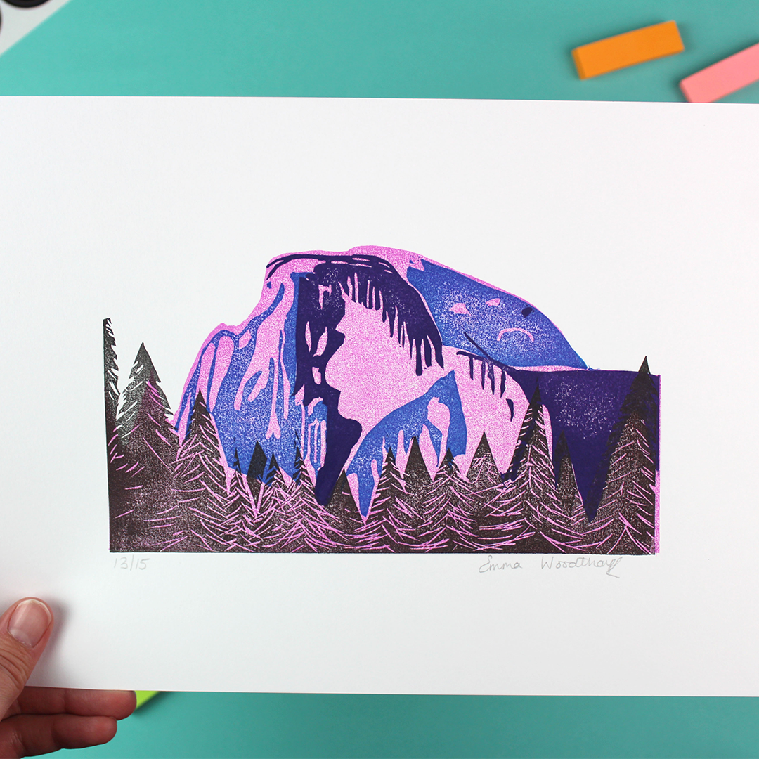 a hand holds up the limited wition lino print of Half Dome, which is signed and numbered