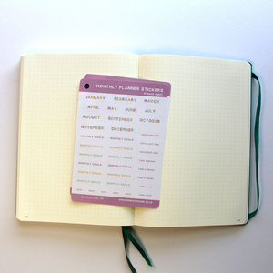 The monthly planner stickers are shown on an open journal, ready for some bullet-journalling.