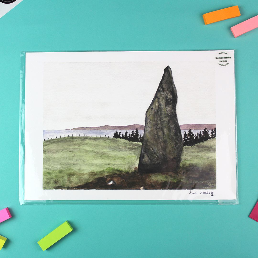 The image shos a landscape orientated print of a watercolour lanscape/seascape. In the foreground stands a stone shard known as the druid stone - a standing stone on the isle of arran. In the distance can be seen the sea and beyond, purple mountaind.