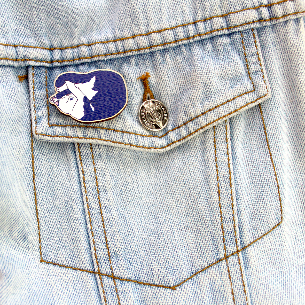 The blue and white cute cat wooden pin badge is shown attached to a denim jacket pocket